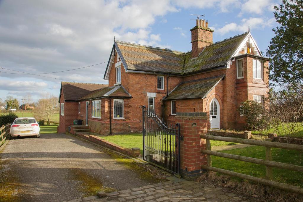 una vieja casa de ladrillo con un coche aparcado delante de ella en Moss Cottage, en Bickley