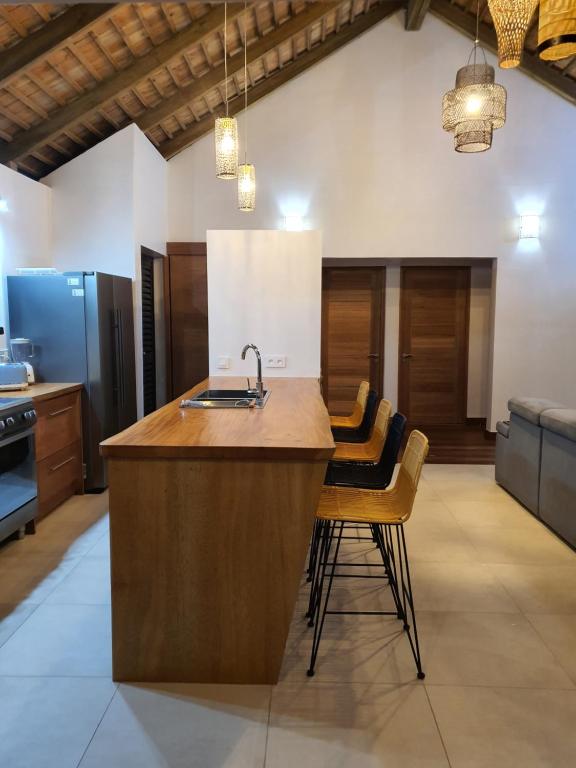 a kitchen with a counter with a sink and chairs at Moorea Lodge in Temae