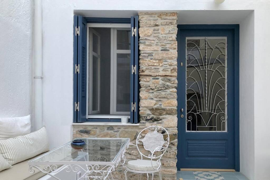 una puerta azul con una mesa de cristal y una silla en Petra stonehouse near the Port, en Panormos Skopelos