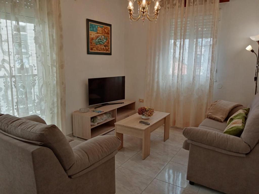 - un salon avec deux chaises et une télévision à écran plat dans l'établissement Apartamento A Canteira, à O Grove