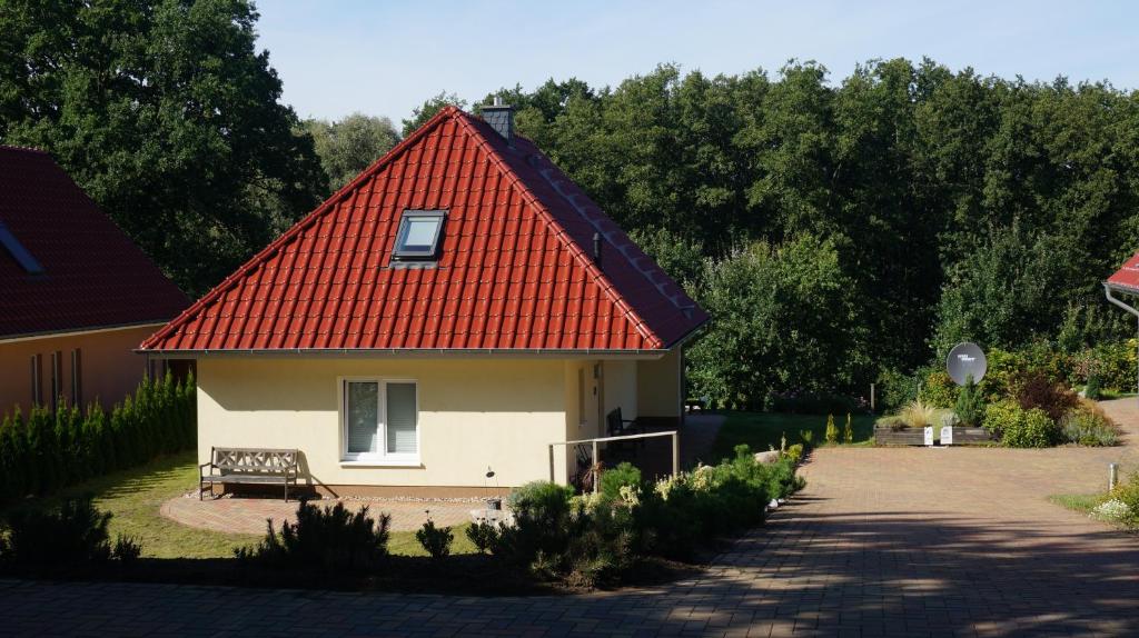 ein kleines Haus mit rotem Dach und einer Bank in der Unterkunft Lakeside House Strasen in Wesenberg