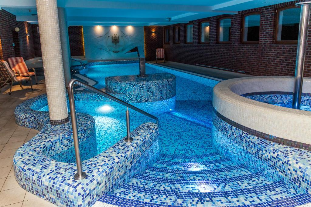 basen z niebieskimi płytkami na podłodze w obiekcie Palac Mortegi Hotel & SPA- Restauracja Szlachecka, SPA, Basen, Sauny, Jazda Konna, Mini Zoo- Luksus, Relaks i Przyroda w jednym! w mieście Lubawa