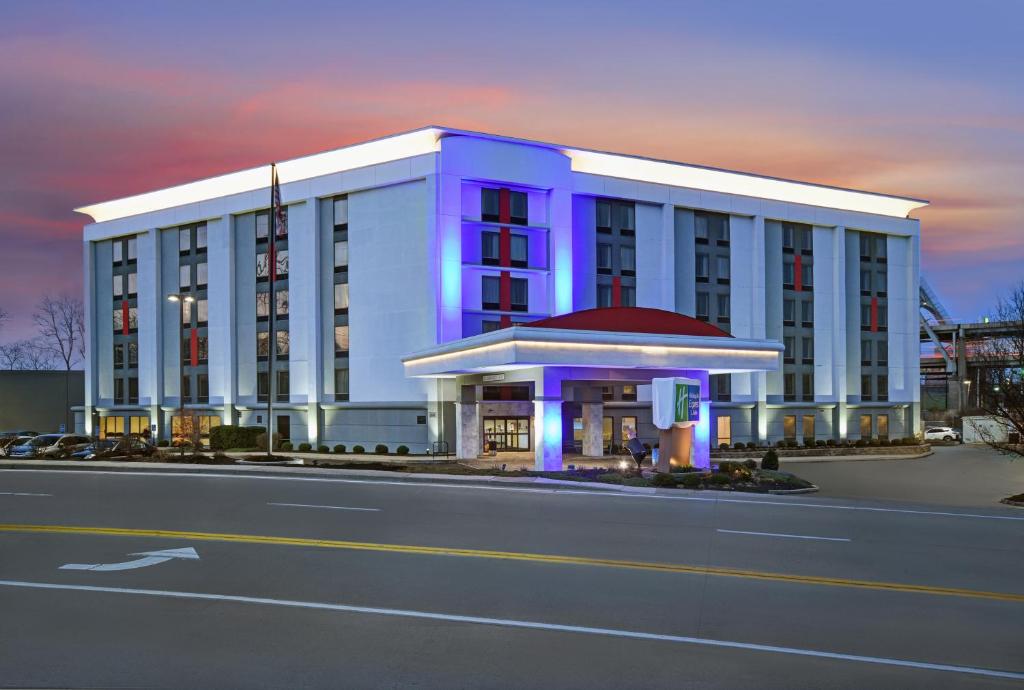 Holiday Inn Express & Suites Cincinnati Riverfront, an IHG Hotel في كوفينغتون: مبنى أبيض كبير مع ضوء أرجواني