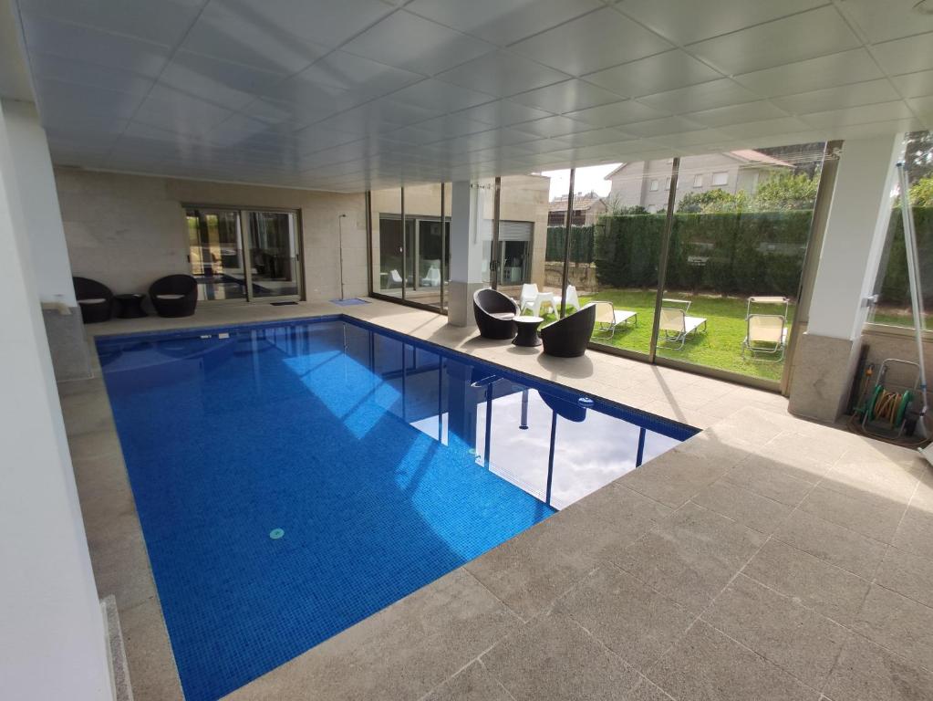 uma grande piscina com água azul numa casa em Sanxenxo Casa Rial 47 con PISCINA CLIMATIZADA em Sanxenxo