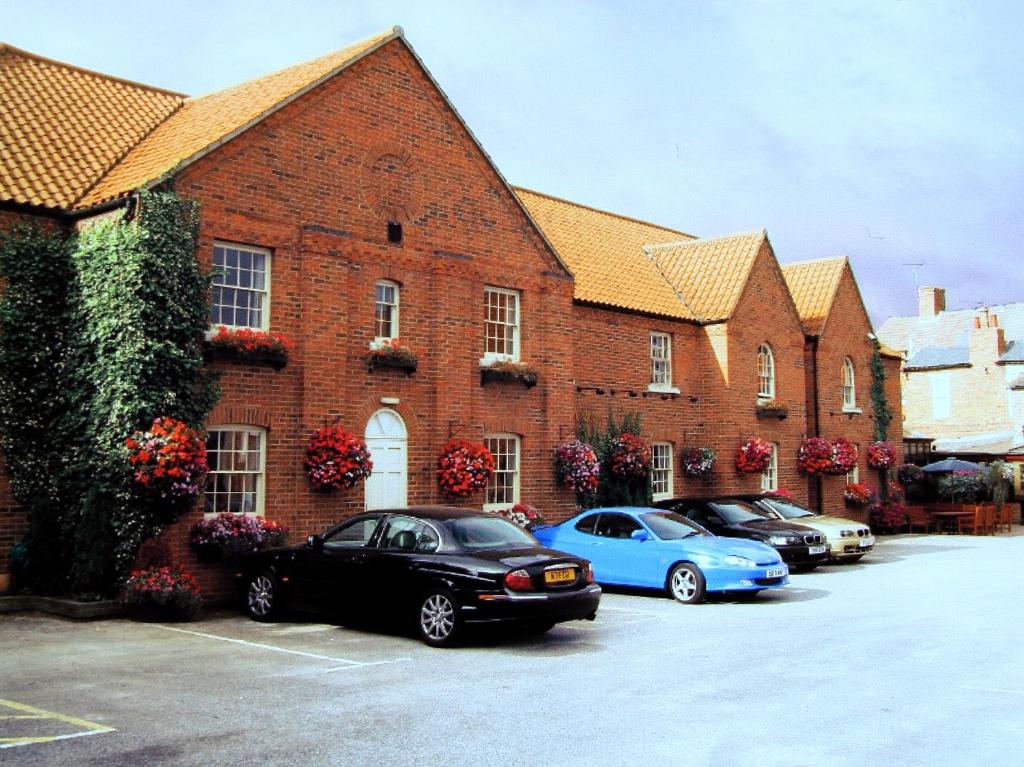 un grupo de coches estacionados frente a un edificio de ladrillo en Millgate House Hotel en Newark upon Trent