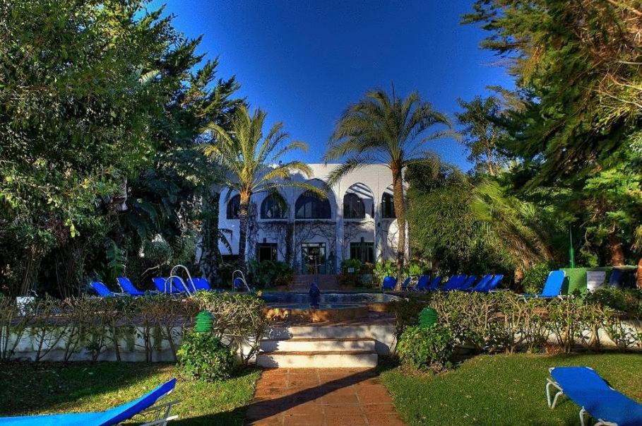 a house with blue lawn chairs and a pool at Hurricane Beach Hotel in Tarifa