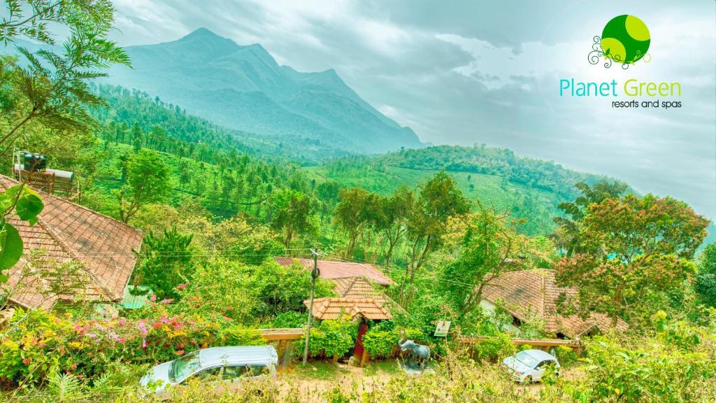 a group of houses with mountains in the background at Planet Green Plantation Resorts, Wayanad, Kerala in Kalpetta