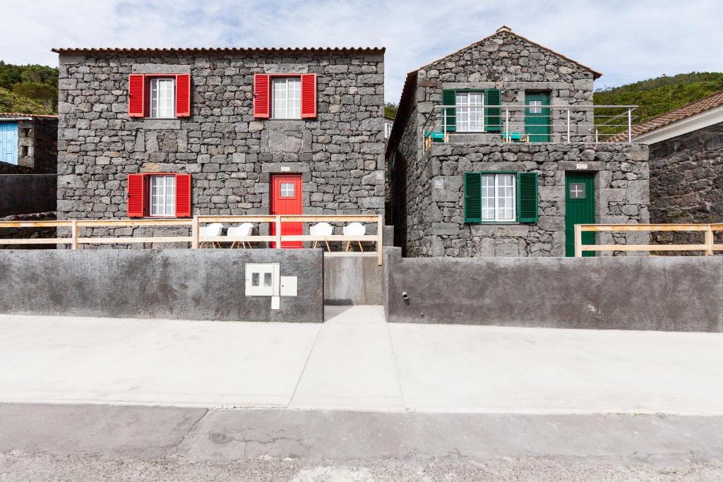 two stone buildings with red and green doors at Alojamentos Pontas Negras in Pontas Negras