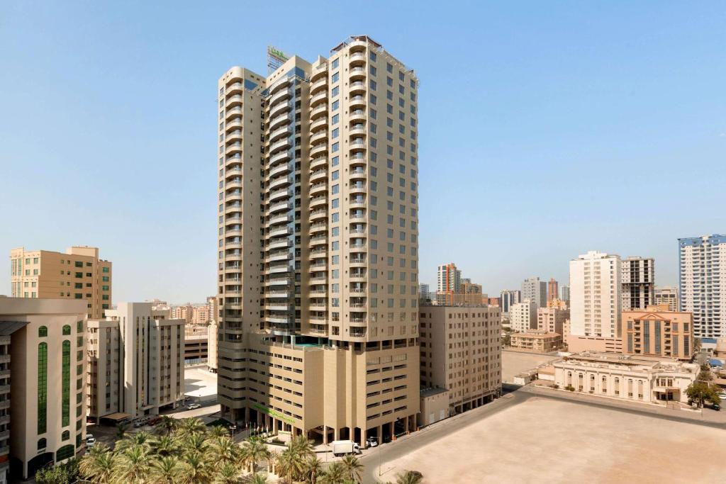 a large tall building in a city with buildings at Wyndham Garden Manama in Manama