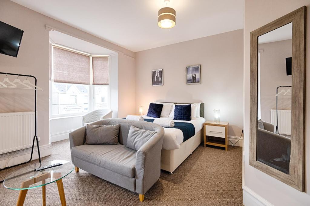 a bedroom with a bed and a chair and a mirror at Alexandra House in Swansea
