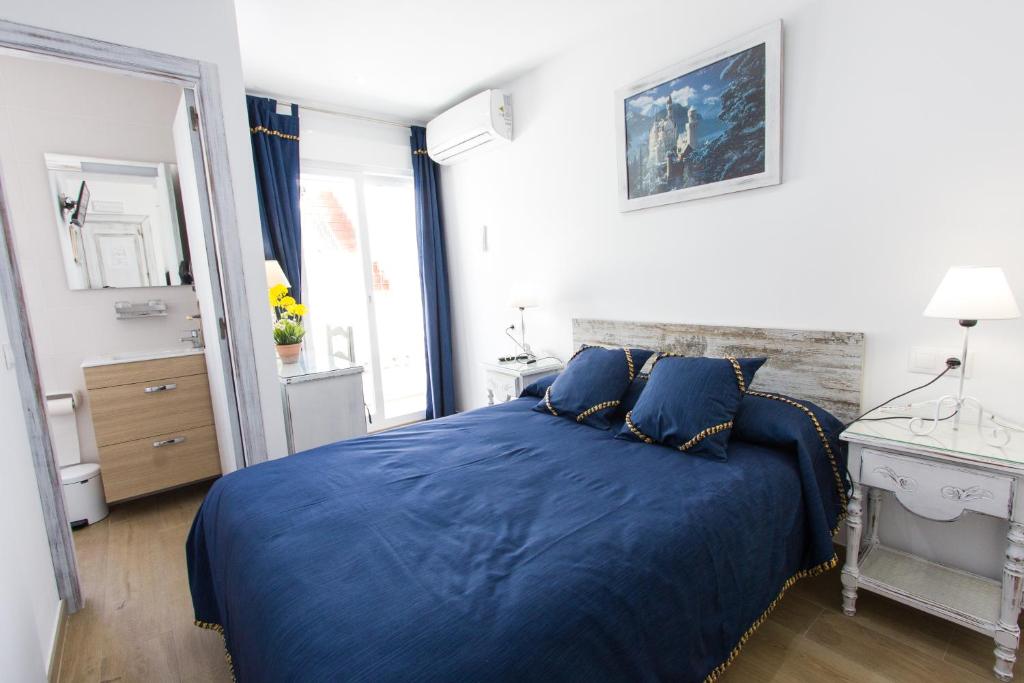 a bedroom with a blue bed and a mirror at Hostal La Estrella in Marbella