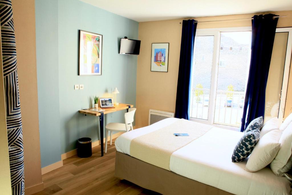 a bedroom with a bed and a desk and a window at Logis Hôtel Marguerite d'Anjou in Angers