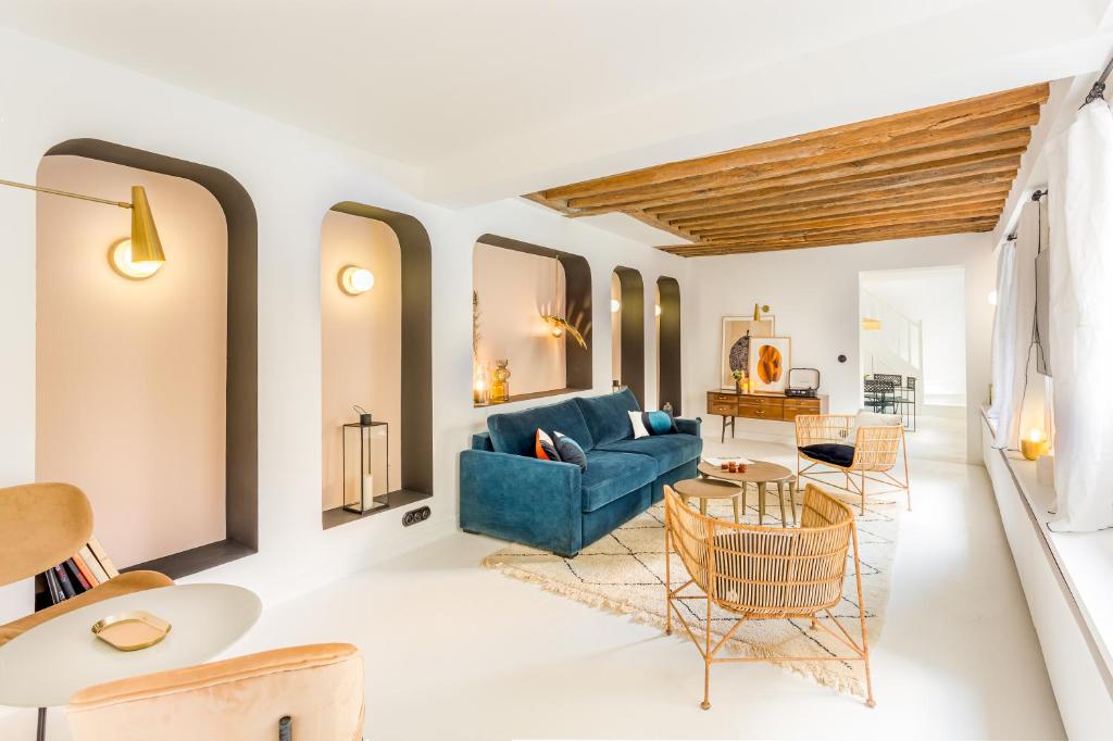 un salon avec un canapé bleu et des chaises dans l'établissement Habitat Parisien - Louvre Rivoli, à Paris