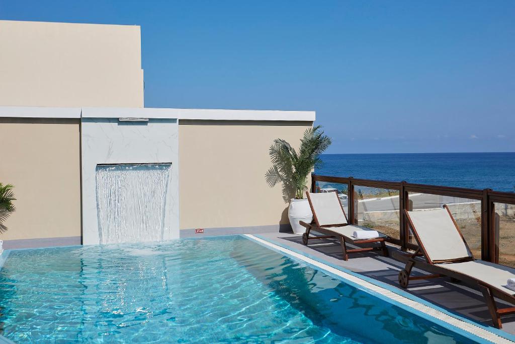 a swimming pool with two chairs and the ocean at Villa Andreas in Panormos Rethymno
