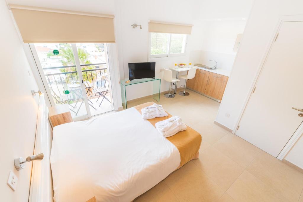 a bedroom with a bed and a desk and a window at Chrielka Hotel in Limassol