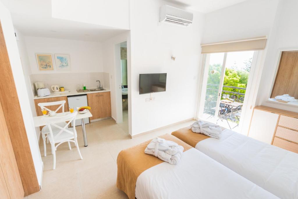 a white room with two beds and a table at Chrielka Hotel in Limassol