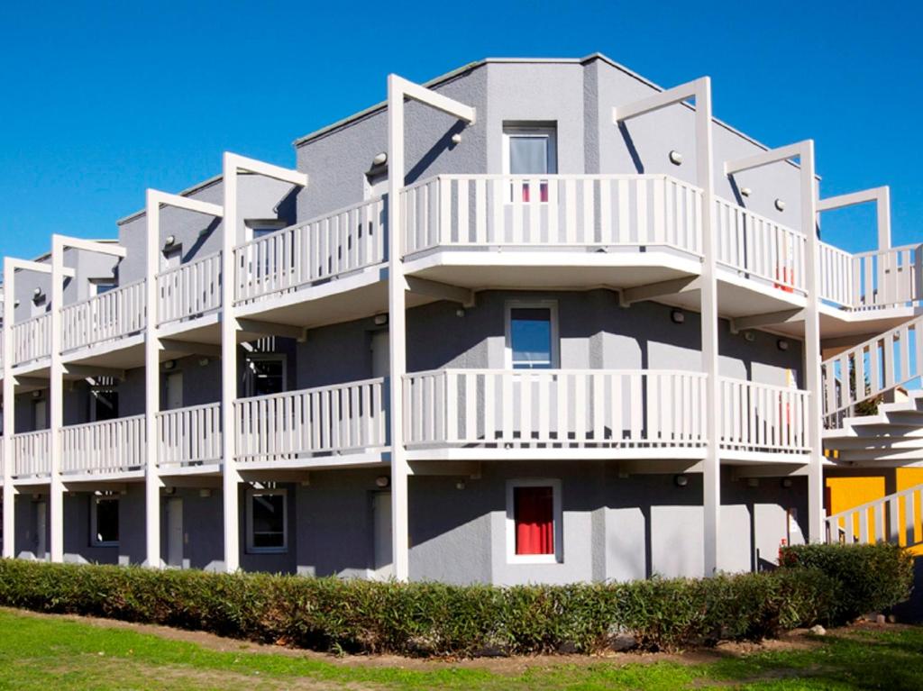 - un bâtiment avec des balcons blancs et une porte rouge dans l'établissement Première Classe Toulouse Nord - L'Union, à LʼUnion