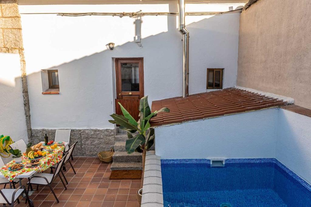 una casa con piscina junto a una mesa y una mesa en Casa Rural Valsain Lodge -Piscina abierta! en La Pradera de Navalhorno