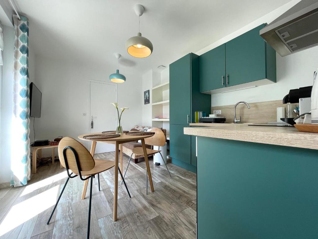 une cuisine avec des armoires vertes, une table et des chaises dans l'établissement STUDIO, UN HAVRE DE PAIX - BIDART ERRETEGIA, à Bidart