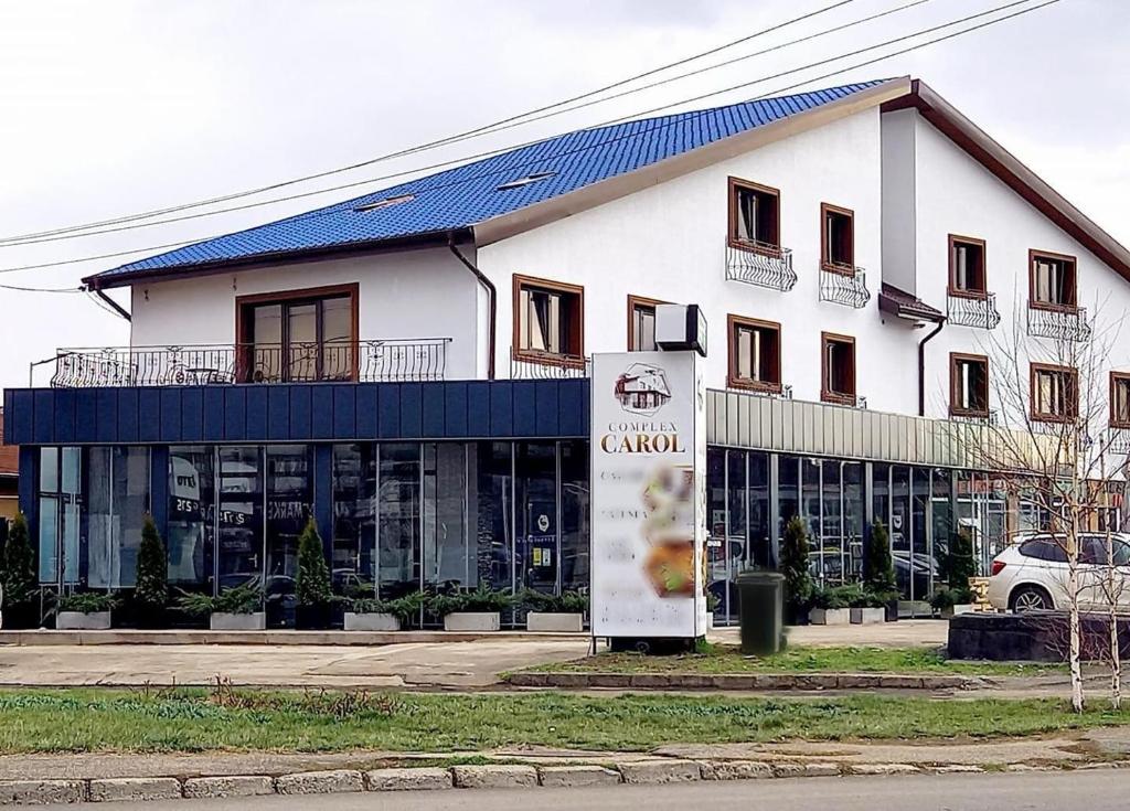 a large white building with a sign in front of it at Complex Carol in Buzau