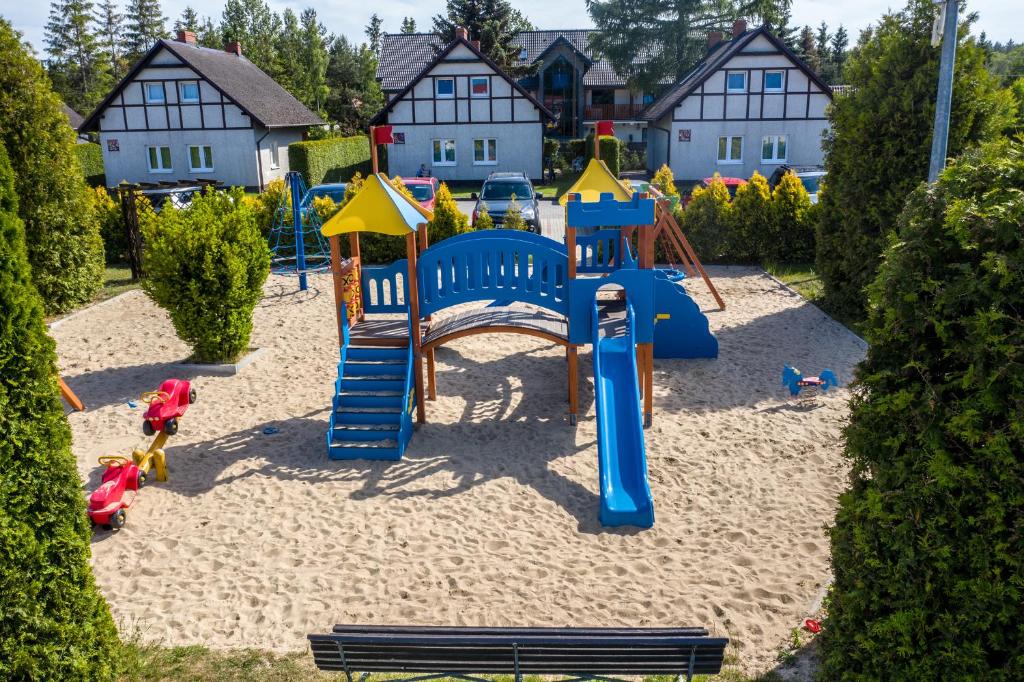 a playground in the sand with houses in the background at Morska Kraina in Białogóra