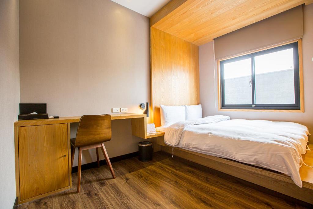 um quarto com uma cama, uma secretária e uma janela em Easylazy Inn em Taichung
