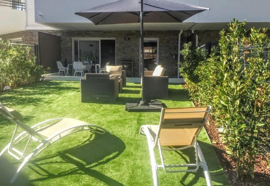 キャヴァレール・シュル・メールにあるModerne T2 avec garage ,très calme avec jardin privé et piscine, à 400m du centre ville et des plages, WIFI remise supplémentaire de 10 pourcent pour une location à la semaineのパティオ(芝生の上にパラソルと椅子付)