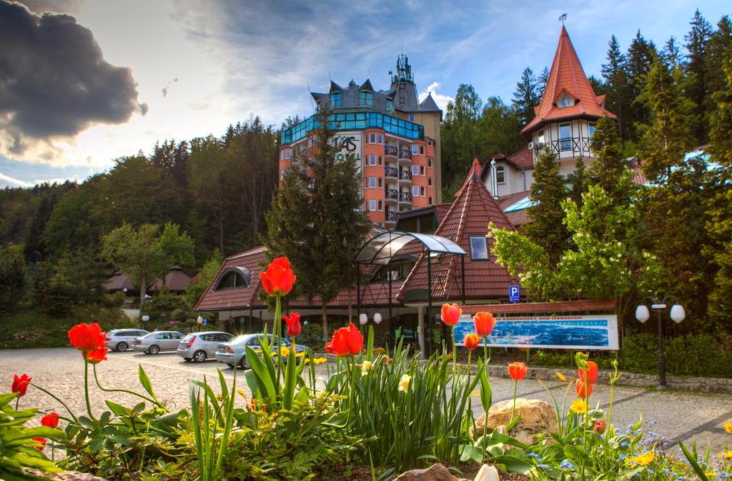 Hotel entrance with bright red tulips in foreground, parked cars and turreted roofs beyond.