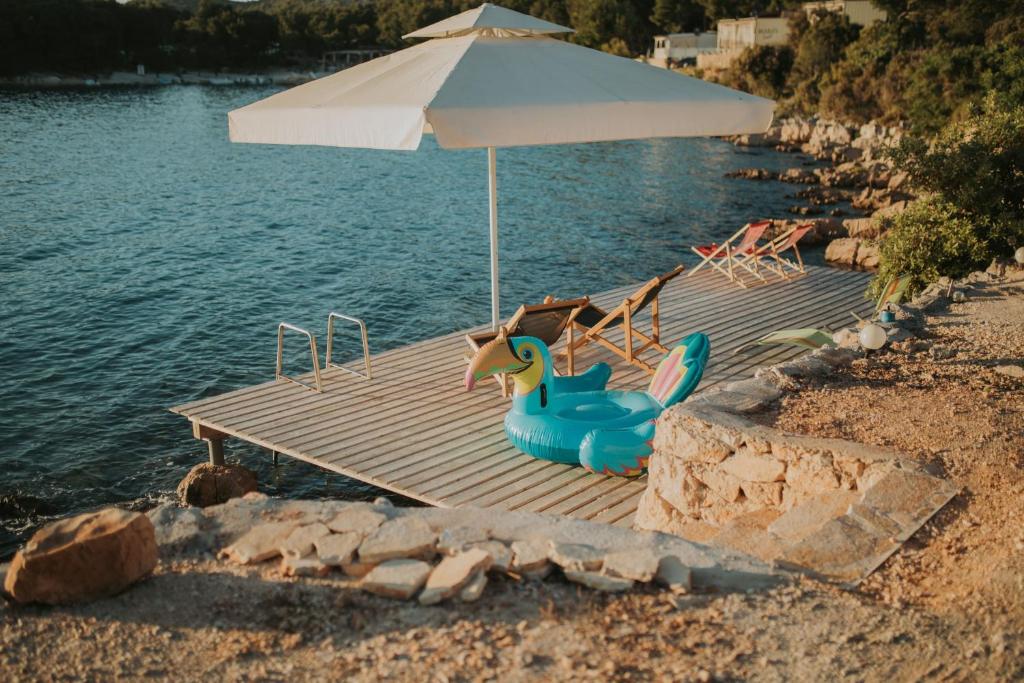 eine Anlegestelle mit einem Sonnenschirm und einigen Stühlen und einem Pool in der Unterkunft Mara's Coast - Ella in Drage