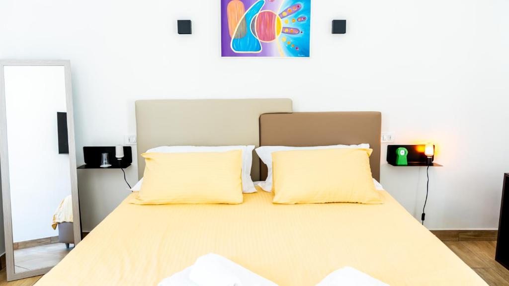a bedroom with a bed with two yellow pillows at Zeta Rooms in Caserta
