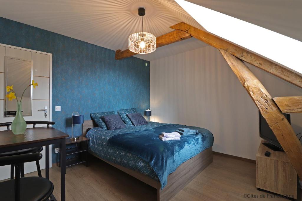 um quarto com uma cama azul, uma secretária e uma mesa em Domaine du clos henri em Essay