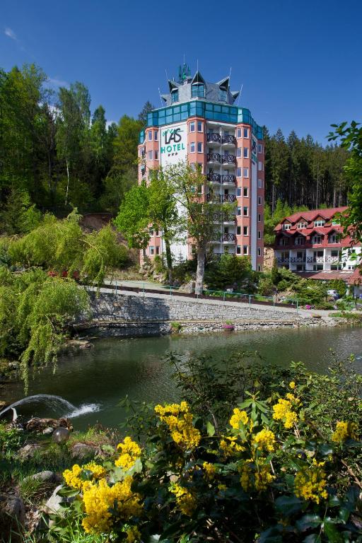 Pink multi-story hotel beside a river with yellow flowers in foreground