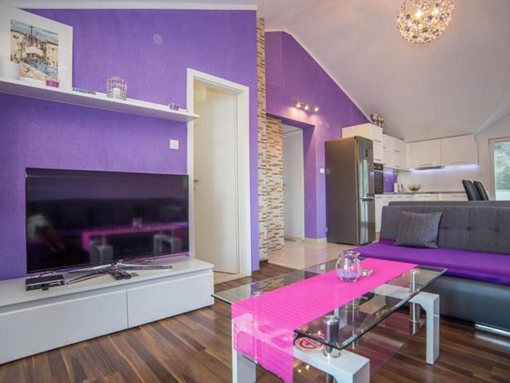 a purple living room with a couch and a table at Apartment Sanja in Povlja