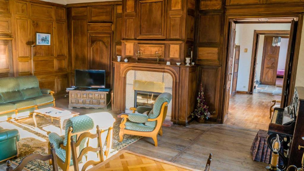 uma sala de estar com lareira e uma mesa e cadeiras em Maison Pierre Loti, gîte historique et spacieux en vallée de la Dordogne em Bretenoux