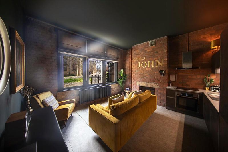 a living room with a couch and a kitchen at The Bells - Luxury Serviced Apartments in Leeds