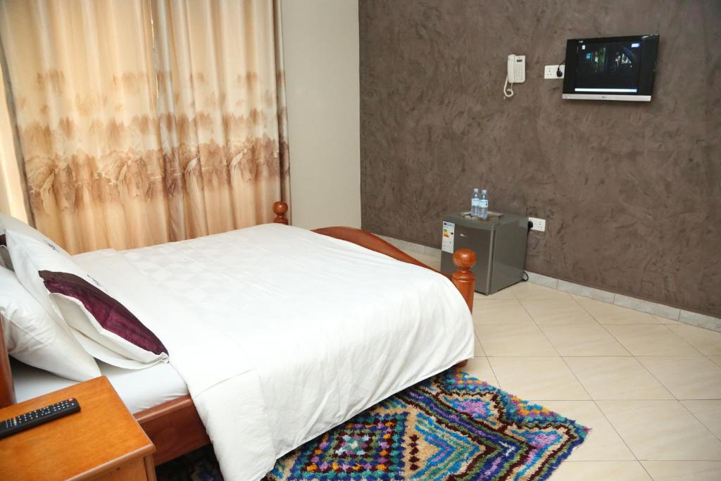 a bedroom with a bed and a television in it at Harts Motel in Kampala