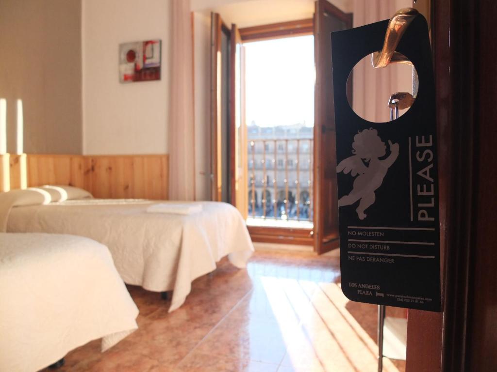 un cartel en una habitación con 2 camas y una ventana en Los Angeles Plaza, en Salamanca