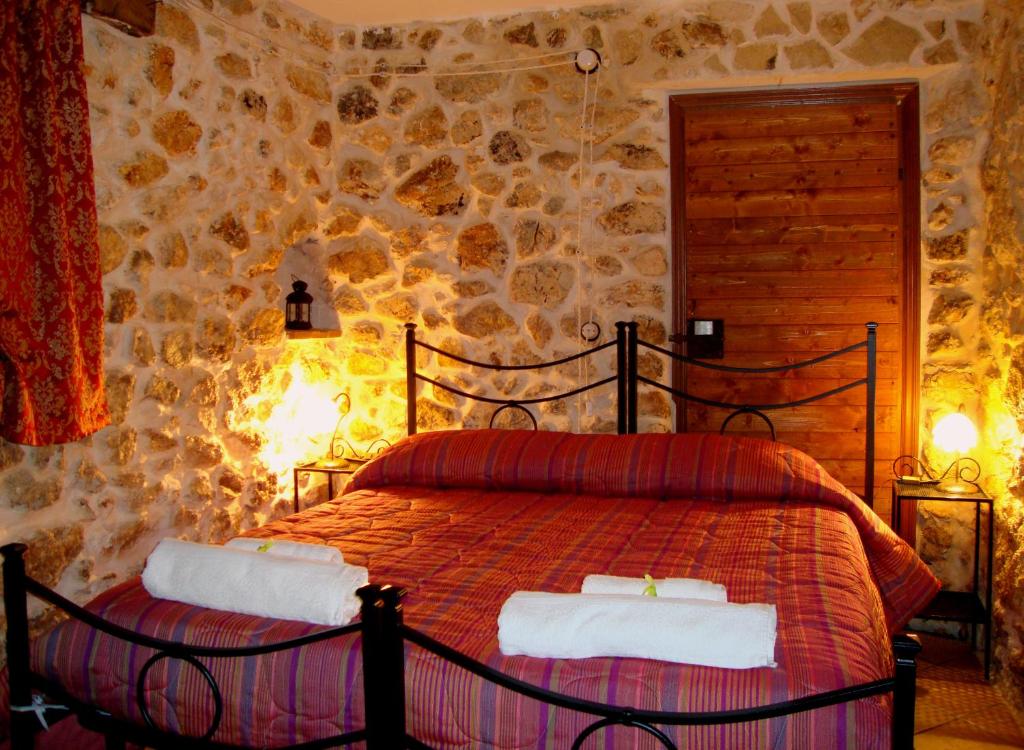 a bedroom with a bed in a stone wall at B&B Foresteria Della Certosa in Collepardo