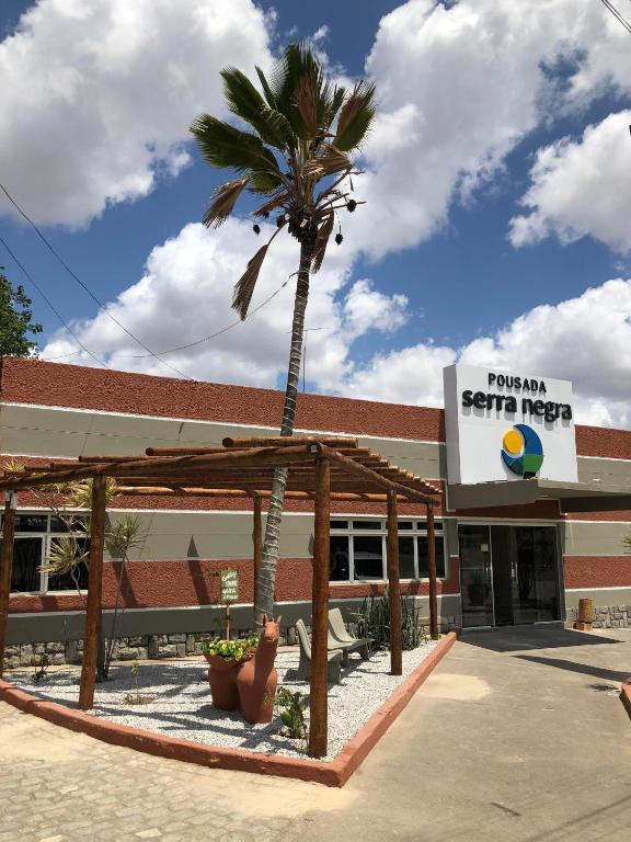a palm tree in front of a building at Pousada Serra Negra in Bezerros