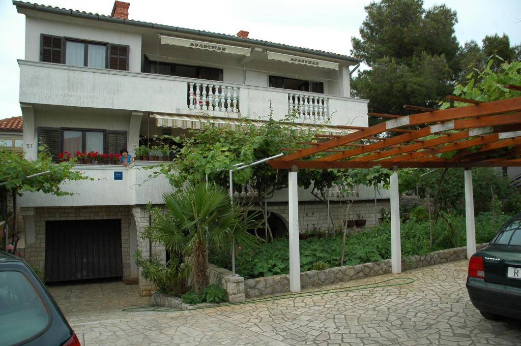 a house with a parking lot in front of it at Apartments Jurina 2 in Krk