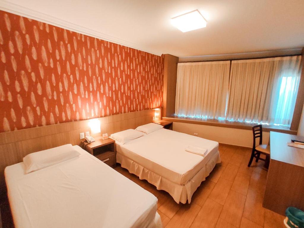 Habitación de hotel con 2 camas, mesa y sillas en Continental Inn, en Foz do Iguaçu