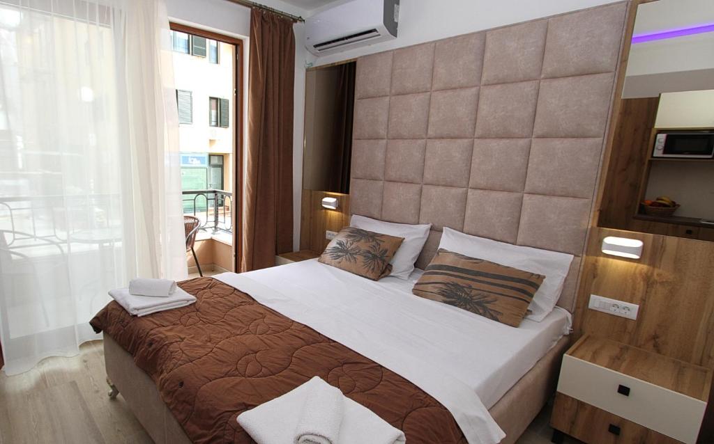 a bedroom with a large bed and a large window at Baron in Budva