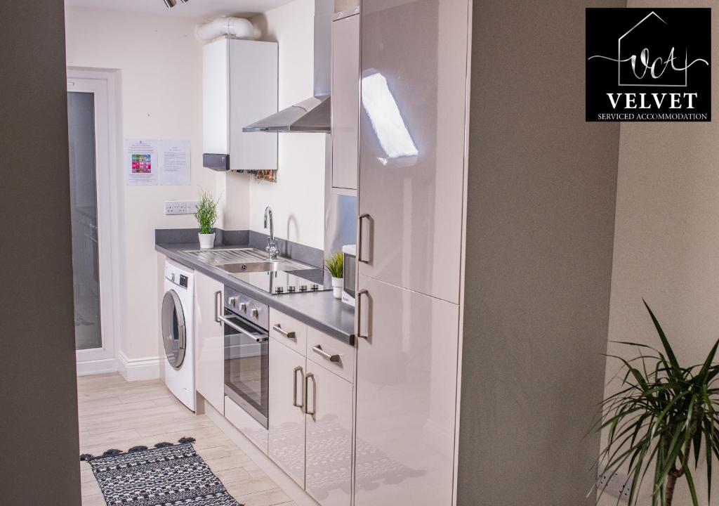 a white kitchen with a sink and a dishwasher at 1 Bed House at Velvet Serviced Accommodation Swansea with Free Parking & WiFi - SA1 in Swansea
