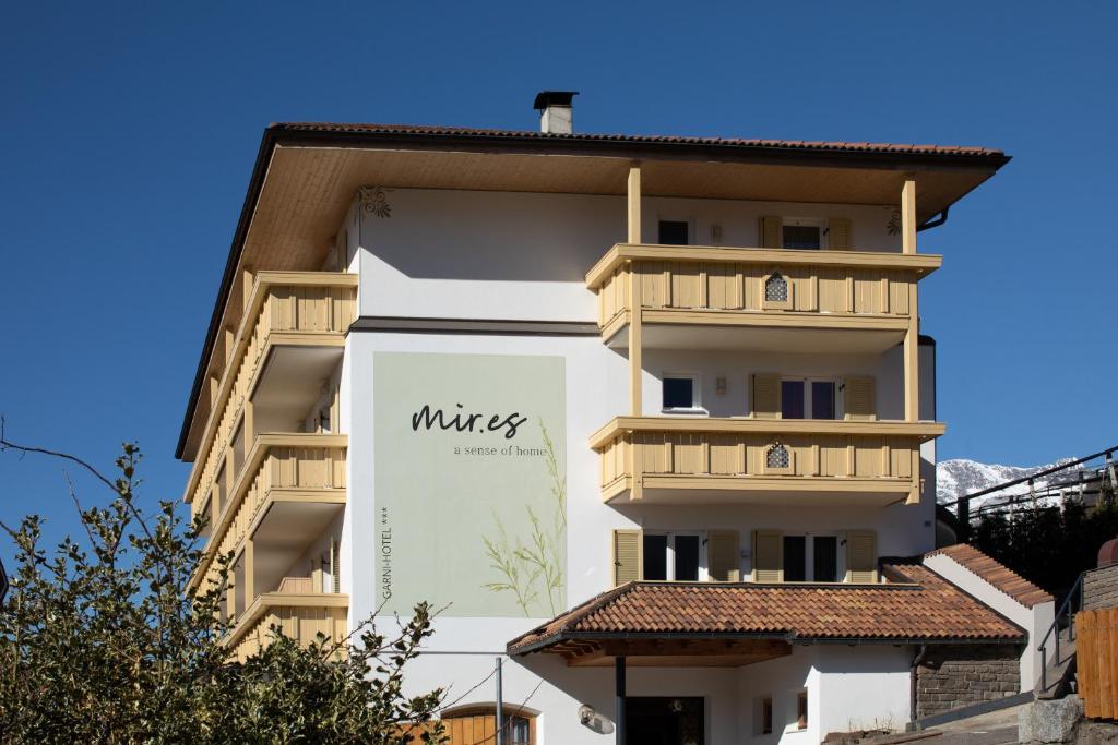 a white building with a sign on the side of it at Garni-Hotel mir.es in Tirolo