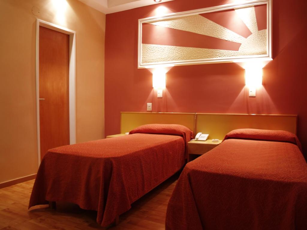 two beds in a room with red walls at Hotel El Cabildo in Buenos Aires