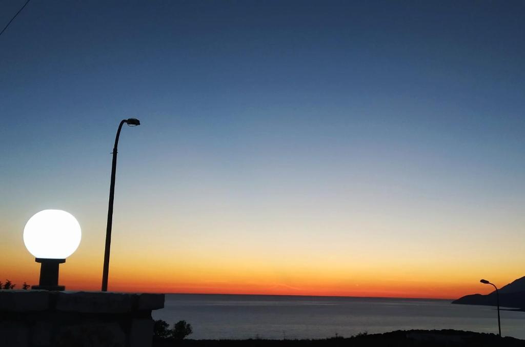 a sunset over the ocean with a street light at Vila Llaka in Himare