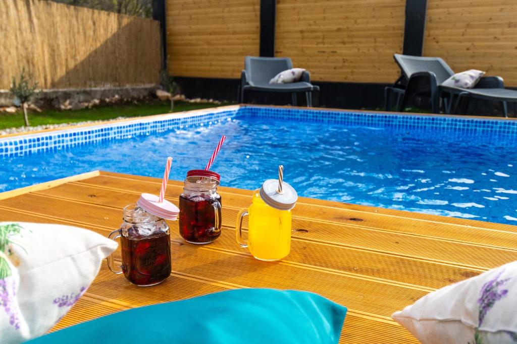 two drinks on a table next to a swimming pool at Casa Amor in Križišće