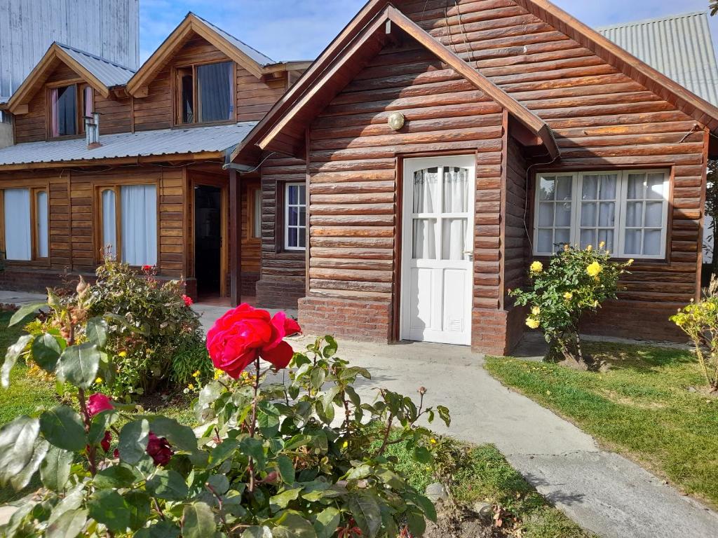 a wooden house with a red rose in front of it at Cabañas Matices in El Calafate