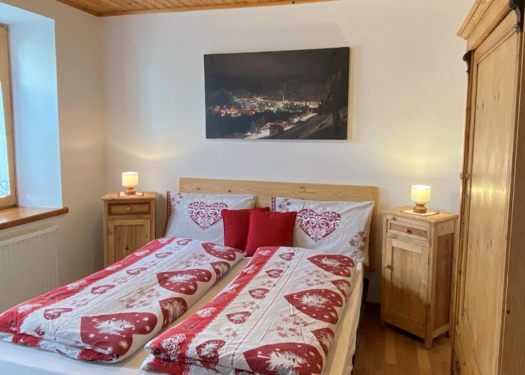 Schlafzimmer mit einem Bett mit roter und weißer Bettwäsche in der Unterkunft Appartamenti Benvenuti in Padola
