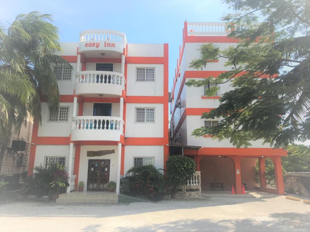 un bâtiment rouge et blanc avec des palmiers devant lui dans l'établissement Easy Inn Hotel, à Belize City